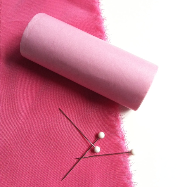 Pins and paper help stabilize silk when stitching. We show a roll of Mood's pink cash register tape here to use for easy paper strips.