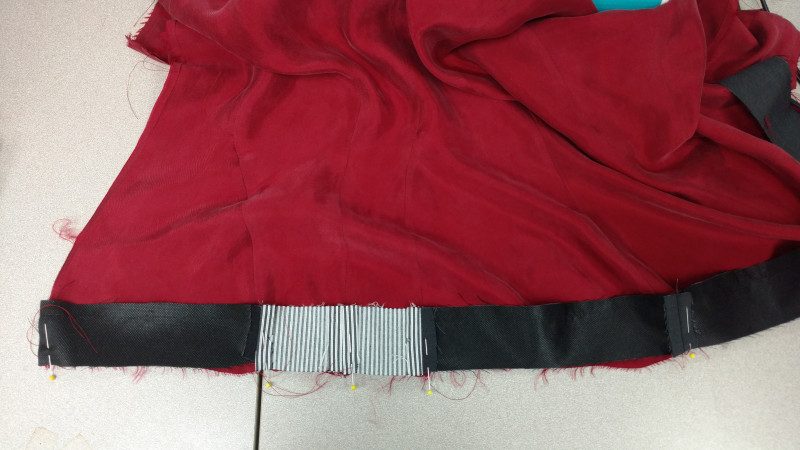 The shorter side of the hem facing gets attached to the lining. The lining will need to be gathered slightly to fit.